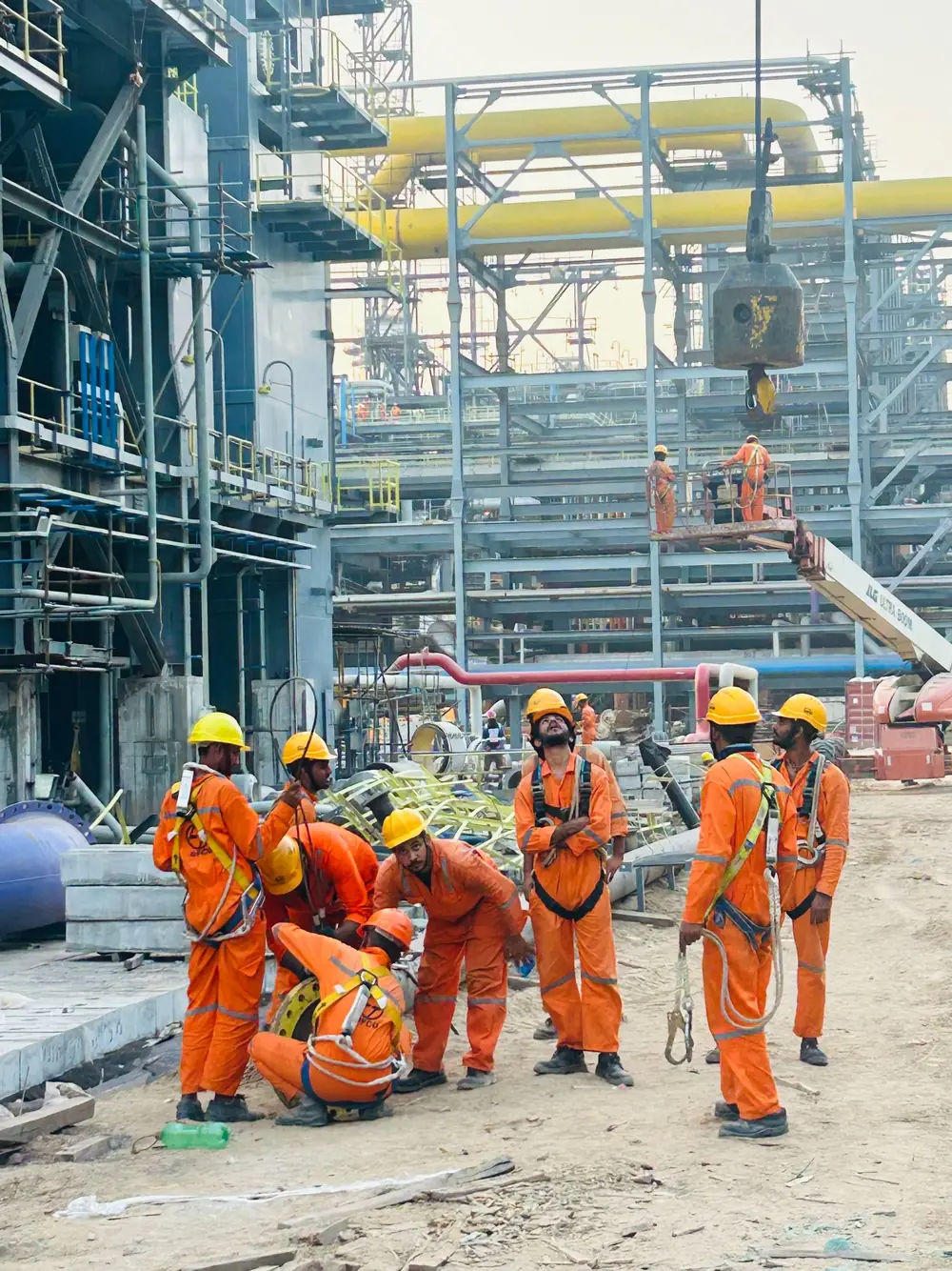 Oil and gas crew in orange coveralls at an industrial site